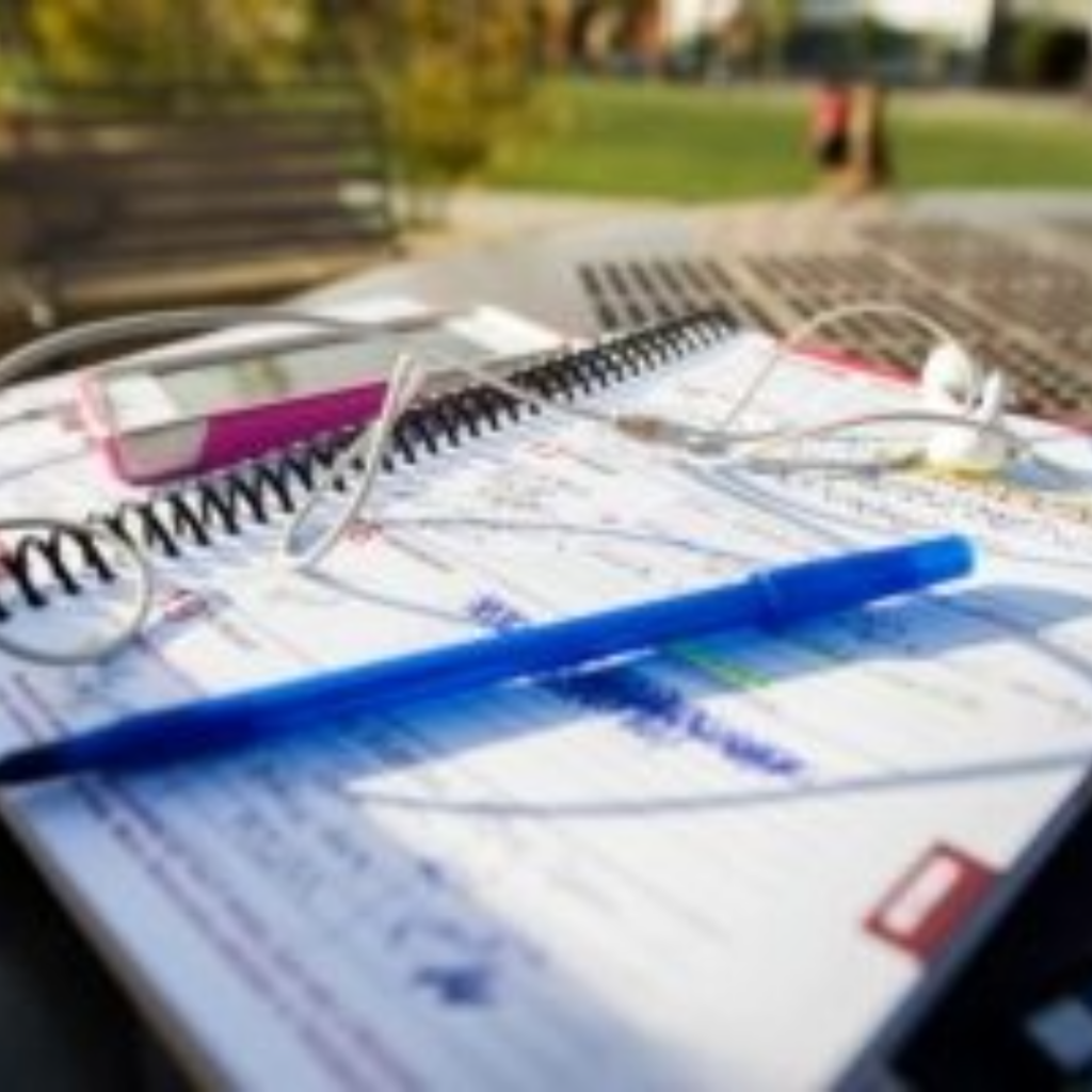 Open notebook with pen and cellular phone outside of Gordon Commons