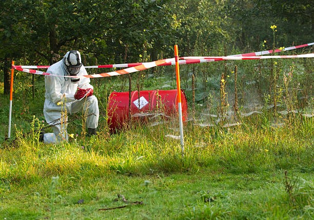 Person in hazmat attire working in a contaminated field. The overlay text is clickable and will take you to the webpage for the Environmental Remediation & Management MS program.