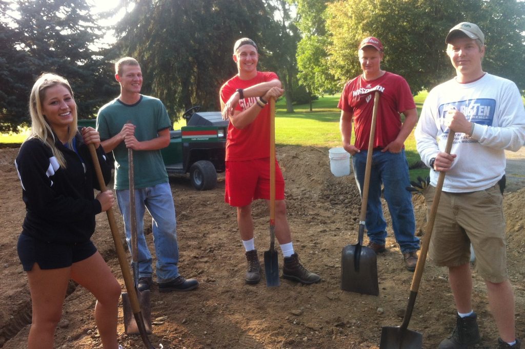 Five people standing around soil pit with shovels. The overlay text is clickable and will take you to the Foundation donation page for the Jaya G. Iyer Soil Science Fund.