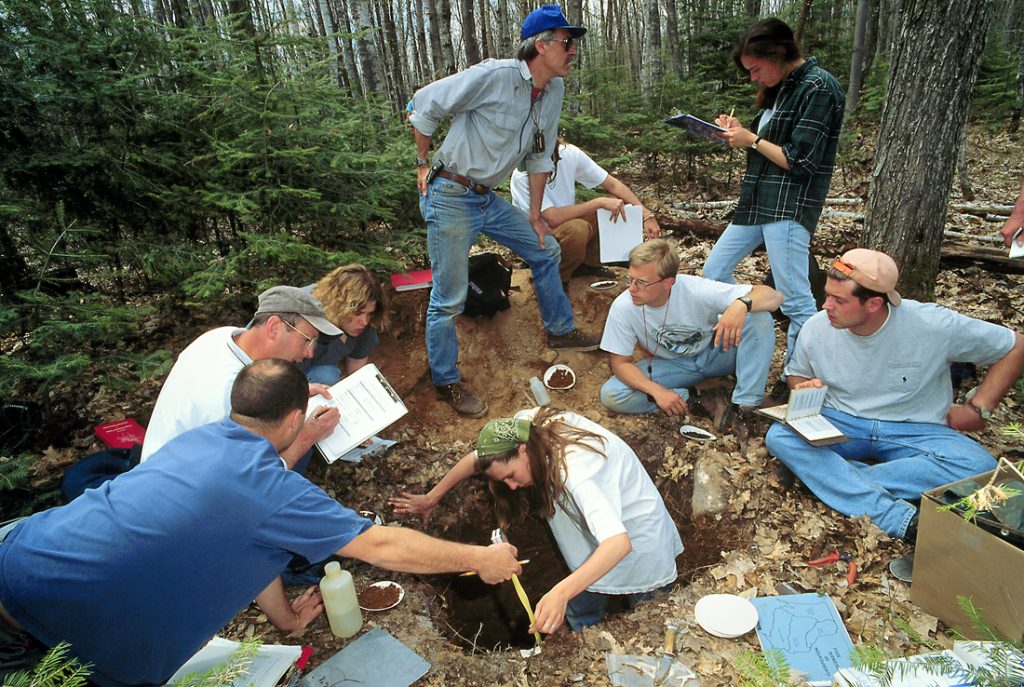 Students sitting around and working in a soil pit. The overlay text is clickable and will take you to the the webpage for the Soil Science MS program.
